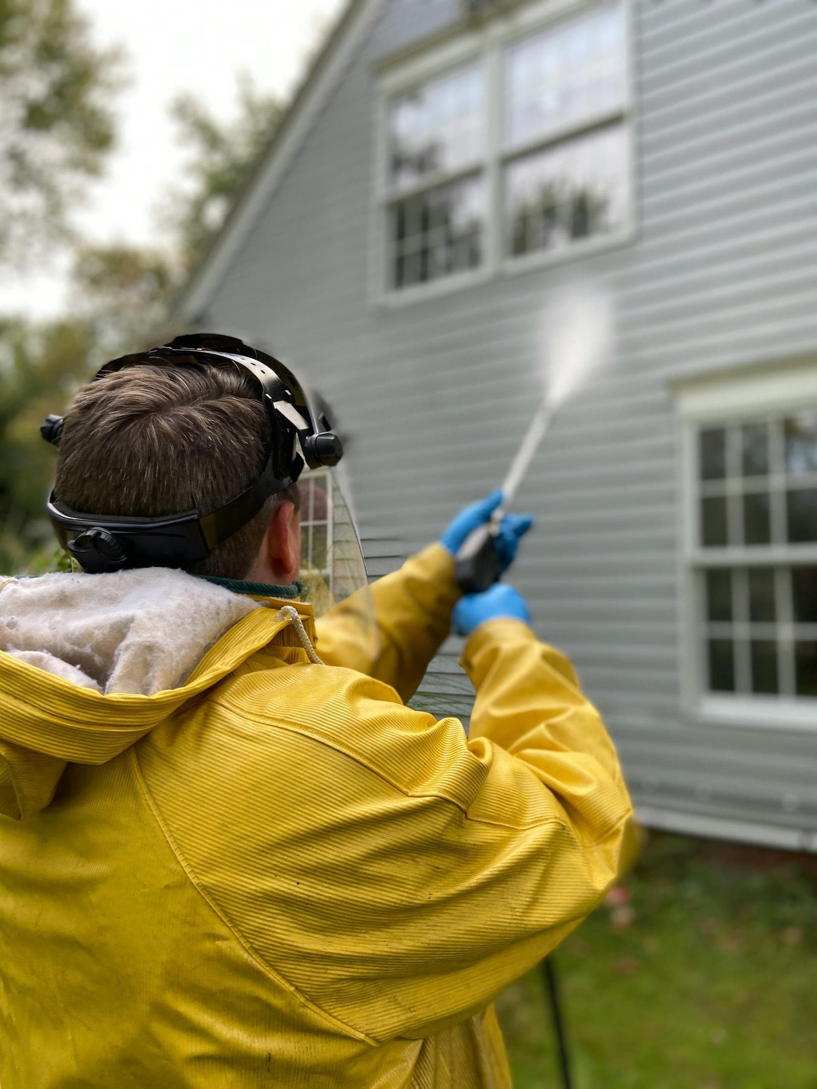 Professional pressure washing a house exterior